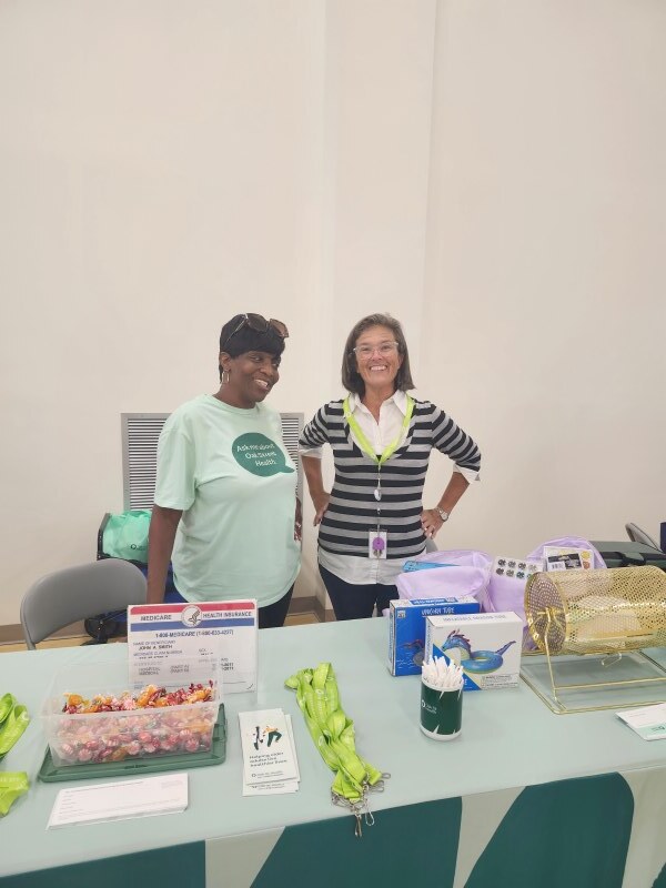 Two ladies standing behind a table.