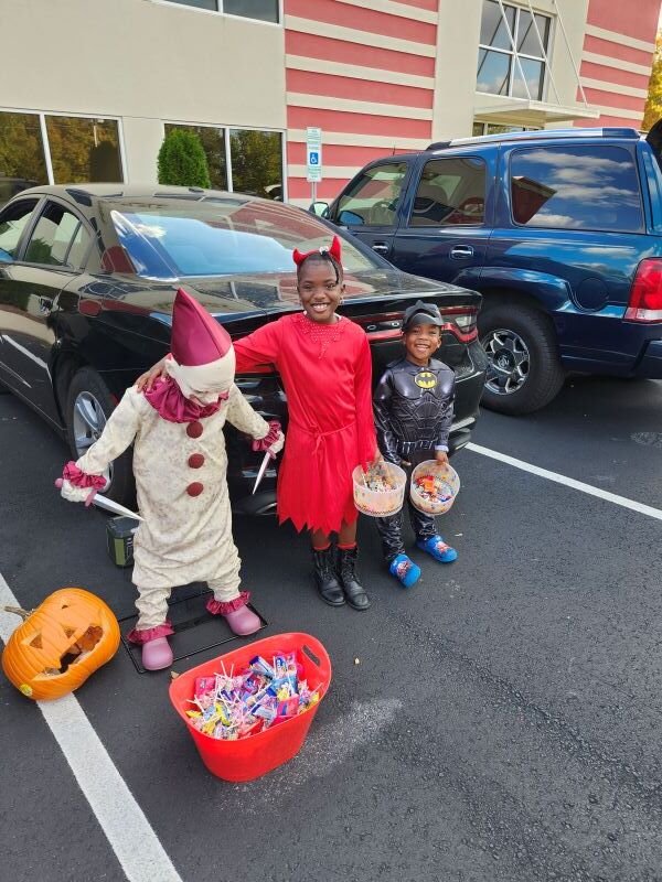 Three kids posing in front of a car.