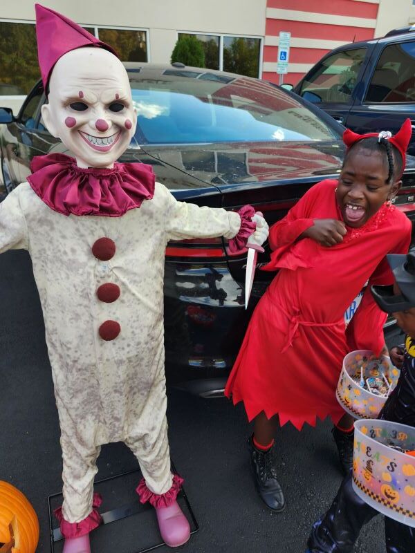 A girl is afraid of another child wearing a scary clown costume.